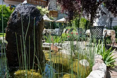 a statue in the middle of a pond in a garden at Hotel Zum Mohren in Tesimo