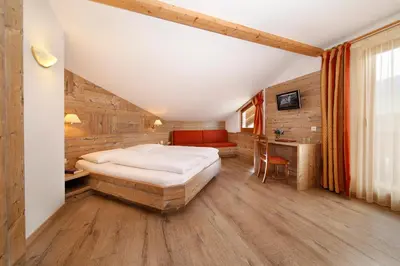 a bedroom with a large bed and a wooden ceiling at Hotel Christine in Gargazzone