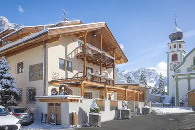 a building with a clock tower in the snow at Chalet Ciasa Alexander in San Cassiano