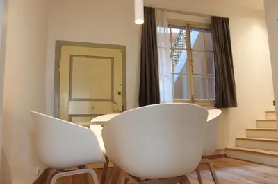 two white chairs in a room with a table and a window at The Court House in Bressanone