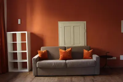 a gray couch with orange pillows in a room at The Court House in Bressanone