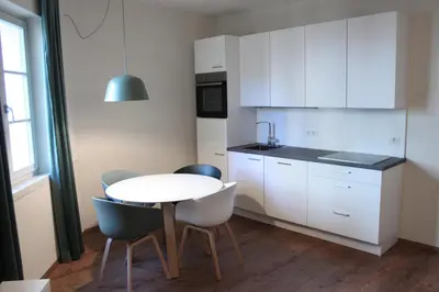 a kitchen with white cabinets and a table and chairs at The Court House in Bressanone