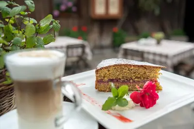 a piece of cake on a plate next to a cup of coffee at Gasthof Tschötscherhof in Castelrotto