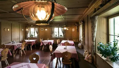 a restaurant with tables and chairs and a chandelier at Gasthof Tschötscherhof in Castelrotto