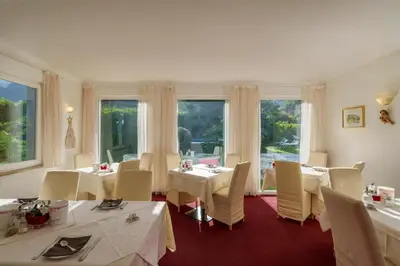 a dining room with white tables and chairs and windows at Hotel Appartement Lahngut in Nalles