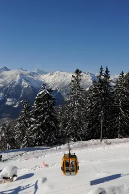 a yellow ski lift in the snow with trees and mountains at Hotel Appartement Lahngut in Nalles