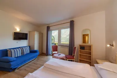 a living room with two beds and a blue couch at Hotel Appartement Lahngut in Nalles