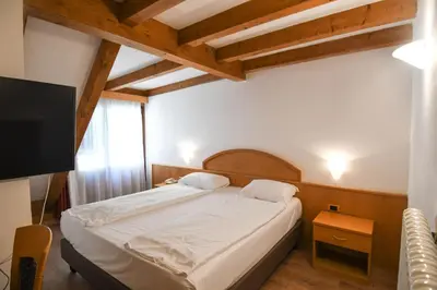 a bedroom with a bed and a flat screen tv at Hotel El Laresh in Moena