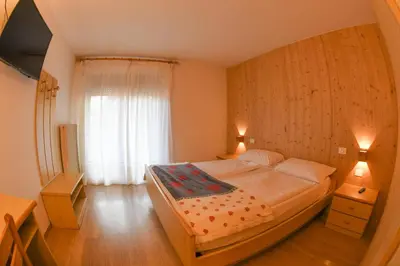 a bedroom with a bed and a large window at Hotel El Laresh in Moena