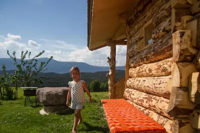 a little girl standing next to a log cabin at Tomasoethof in Castelrotto