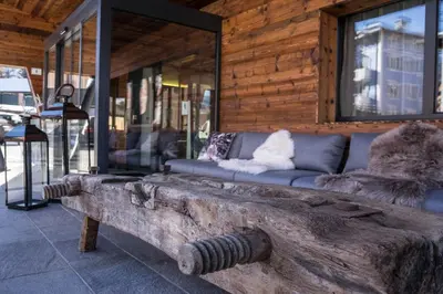 a living room with a couch and a log bench at Hotel San Valier in Cavalese