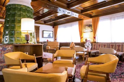 a waiting room with chairs and tables and a green cylinder at Hotel San Valier in Cavalese