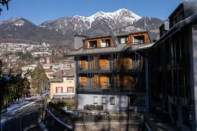 a building with mountains in the background at Hotel San Valier in Cavalese
