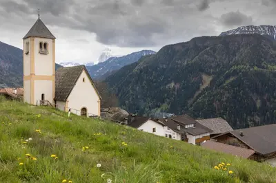 a church on a hill with mountains in the background at Zehentnerhof in Laion
