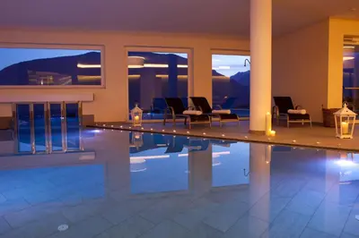 a swimming pool in a house with chairs and lights at Hotel Mitterplatt (Schenna Resort) in Schenna