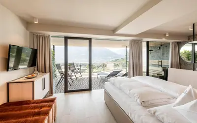 a hotel room with a large bed and a balcony at Hotel Mitterplatt (Schenna Resort) in Schenna