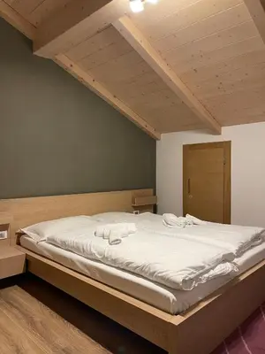 a bedroom with a large bed with white sheets at Mansarda Ciliegio Cavalese in Cavalese