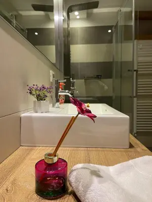 a bathroom with a red vase with a flower in it at Mansarda Ciliegio Cavalese in Cavalese