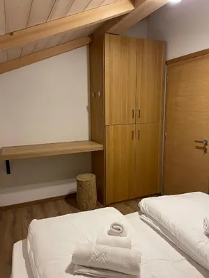 a bedroom with two beds and wooden cabinets at Mansarda Ciliegio Cavalese in Cavalese