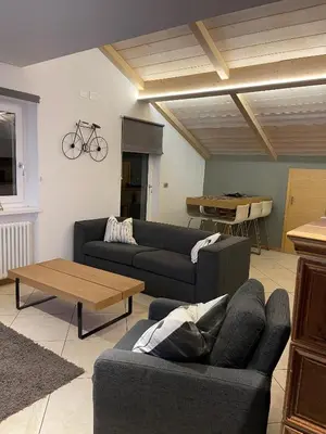 a living room with two couches and a table at Mansarda Ciliegio Cavalese in Cavalese