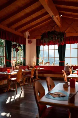 a restaurant with wooden floors and tables and chairs at Hotel Piedibosco in Moena