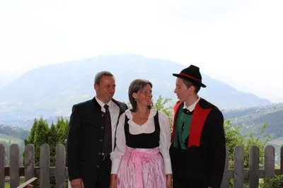 a woman and two men standing in front of a fence at Gasserhof Garni & Apartment in Schenna
