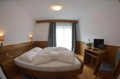 a bedroom with a bed with a window and a desk at Garni Hauenstein in Siusi