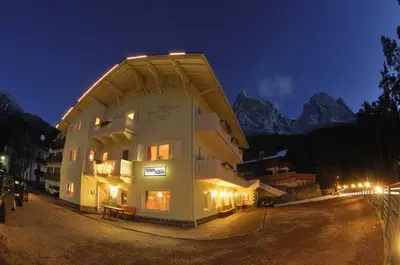 a large building at night with mountains in the background at Garni Hauenstein in Siusi