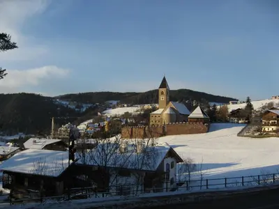 a small town in the snow with a church at Garni Hauenstein in Siusi