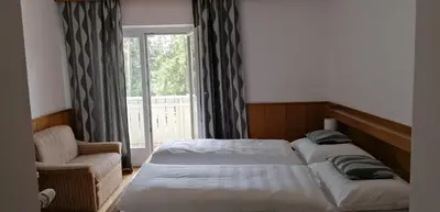 a bedroom with two beds and a chair and a window at Garni Hauenstein in Siusi