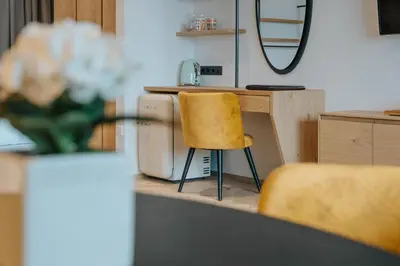 a counter with two yellow chairs and a mirror at Small Hotel Sonne in Tirolo