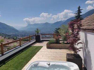 a hot tub on a balcony with mountains in the background at Small Hotel Sonne in Tirolo