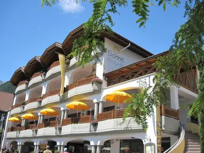 a building with orange umbrellas in front of it at Small Hotel Sonne in Tirolo