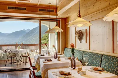 a restaurant with tables and chairs and a balcony at Small Hotel Sonne in Tirolo