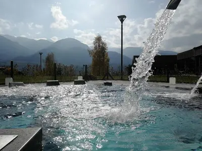 a water fountain in a pool with mountains in the background at CASA GILDA Val di Fiemme - Dolomiti in Cavalese