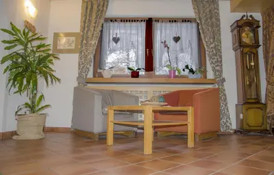 a living room with chairs and a table and a clock at Hotel Casa Alpina - Alpin Haus in Selva di Val Gardena