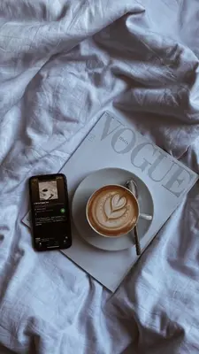 a cup of coffee and a cell phone on a bed at Apartmenthotel Ritterhof Suites & Breakfast in Schenna