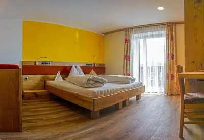 a bedroom with a bed and a yellow wall at Drei Birken in Soprabolzano