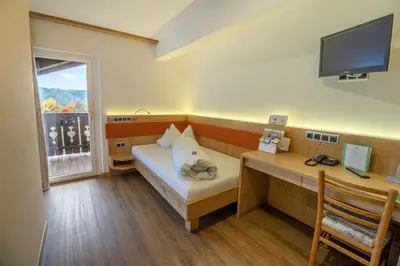 a room with a bed and a desk with a computer at Drei Birken in Soprabolzano