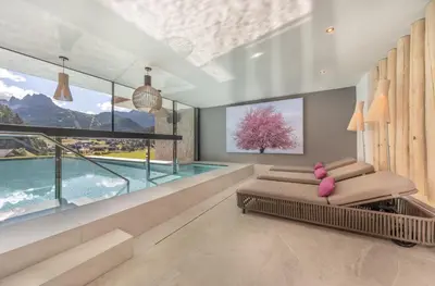 a living room with a bed and a large window at Hotel Rodella in Selva di Val Gardena