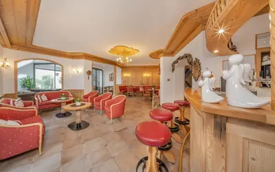 a salon with red chairs and a barber shop at Hotel Rodella in Selva di Val Gardena