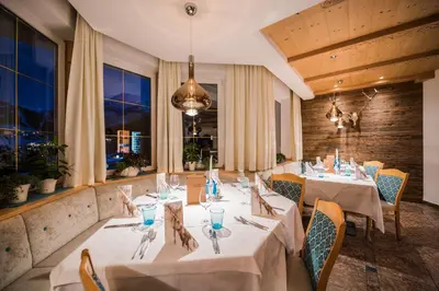 a restaurant with white tables and chairs and windows at Hotel Rodella in Selva di Val Gardena