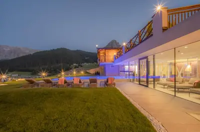 an exterior view of a house with a lawn at Hotel Rodella in Selva di Val Gardena