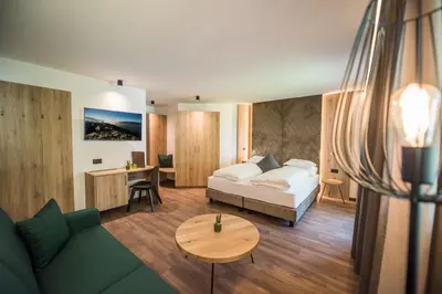a living room with a bed and a table at Vitaurina Royal Hotel in Molini di Tures