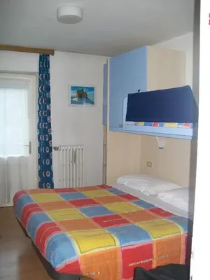 a bedroom with a bed with a colorful blanket at Verda Val in Campitello di Fassa