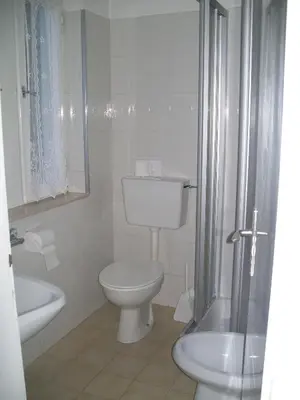 a white bathroom with a toilet and a sink at Verda Val in Campitello di Fassa