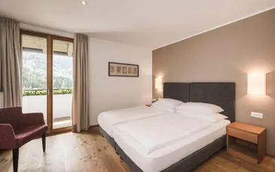a hotel room with a bed and a couch at B&B Villa Angelino in Ortisei