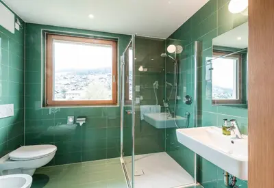 a green bathroom with a toilet and a sink at B&B Villa Angelino in Ortisei