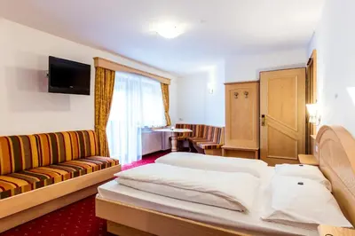 a hotel room with a bed and a couch at Hotel Vernel in Santa Cristina in Val Gardena