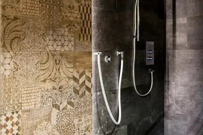 a shower in a bathroom with pipes on a wall at Hotel Vernel in Santa Cristina in Val Gardena